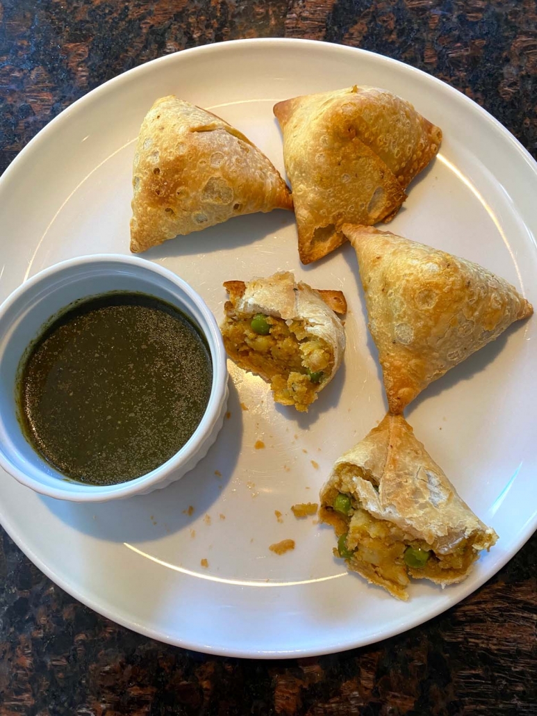 Crispy samosas on a plate with dipping sauce