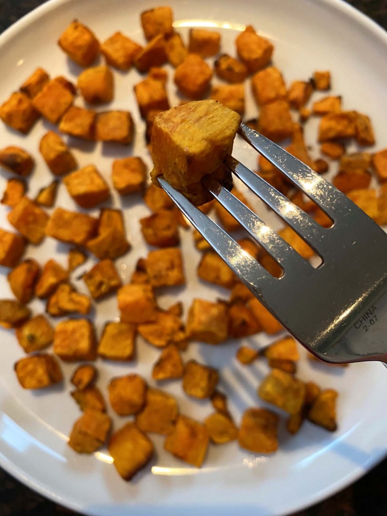 fork with sweet potato held above plate