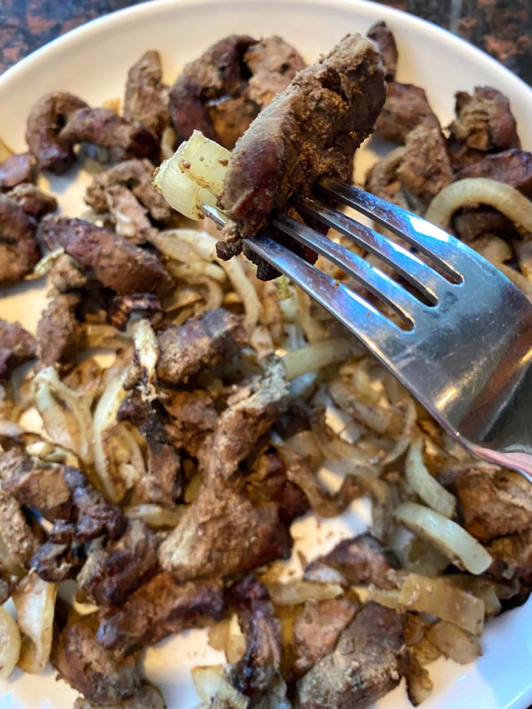 eating beef liver and onions with a fork 