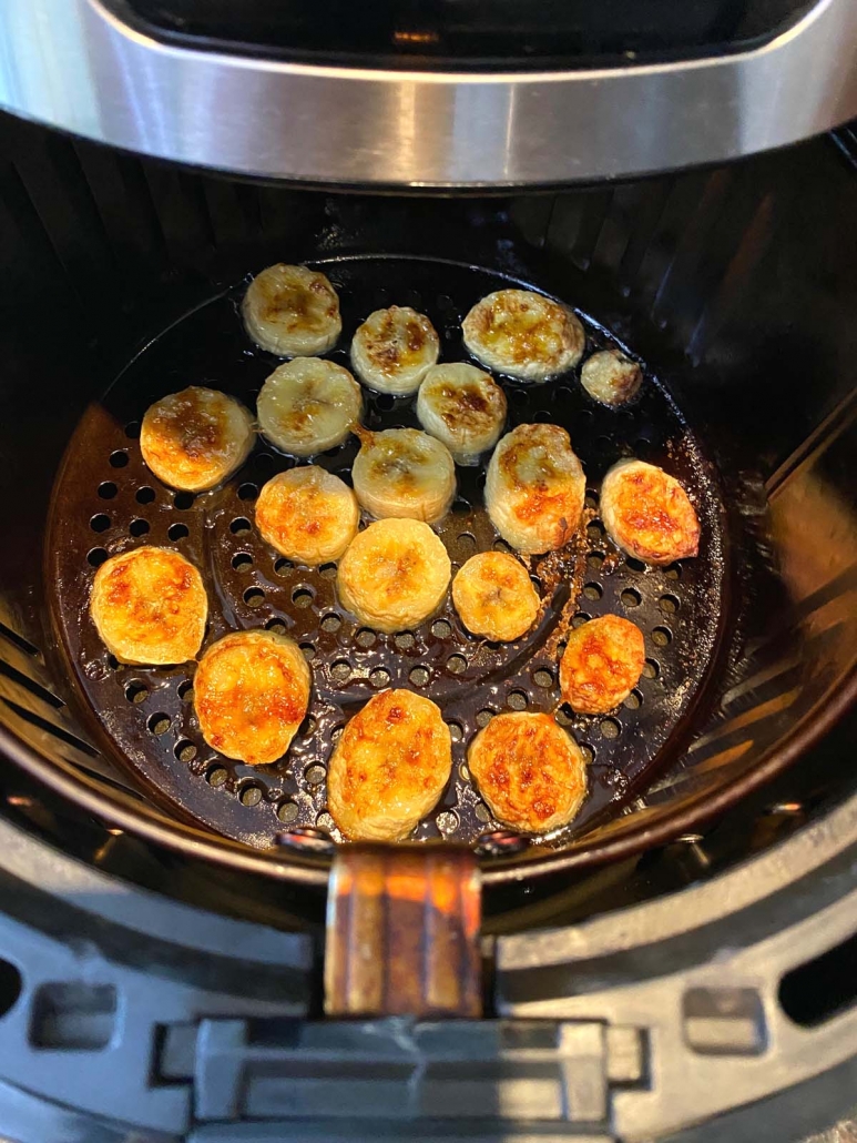 air fryer basket with banana slices cooking inside