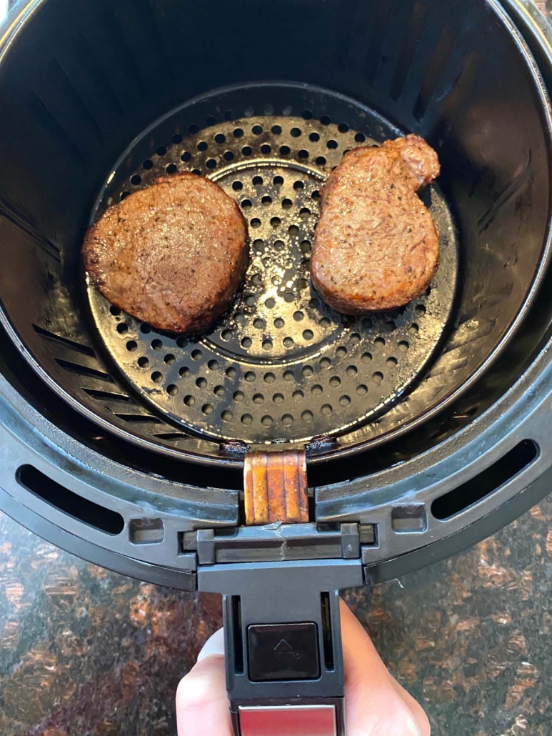air fryer basket with 2 cooked filet mignon steaks