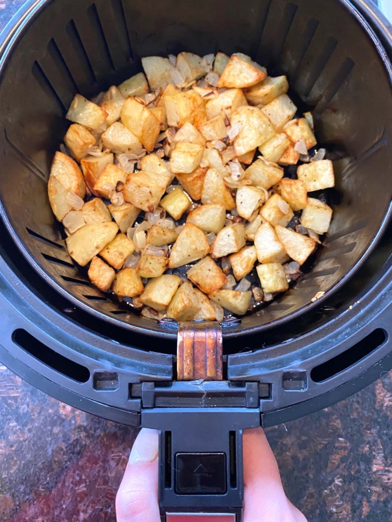air fryer basket filled with potatoes and onions