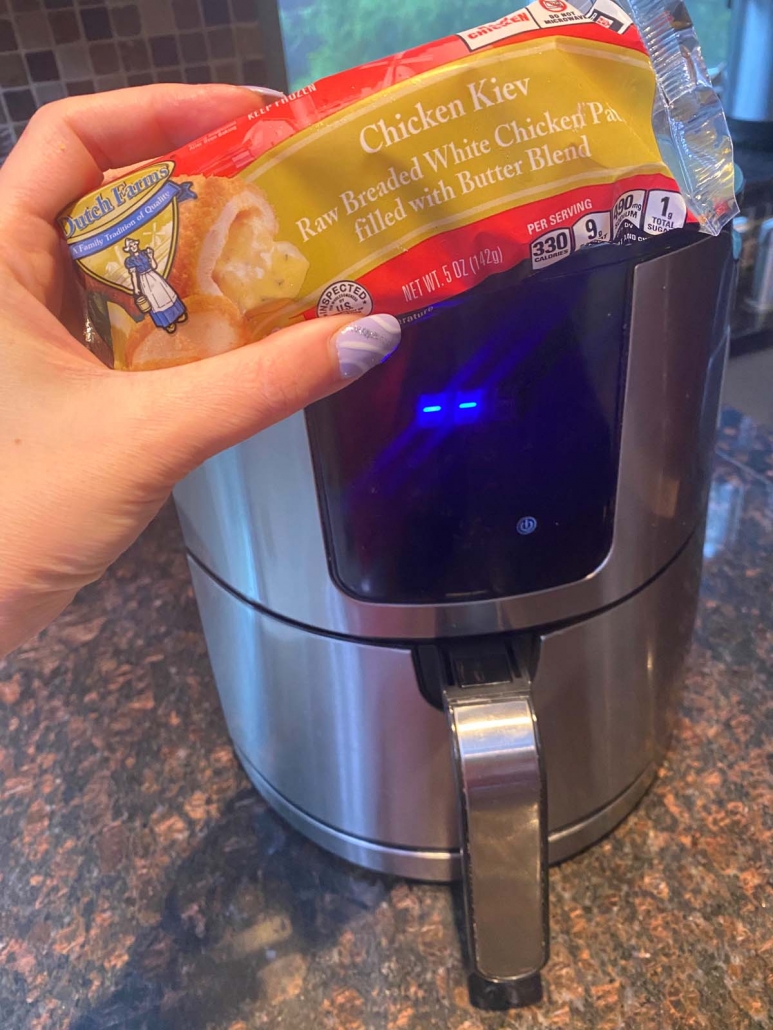 package of frozen chicken kiev held in front of the air fryer