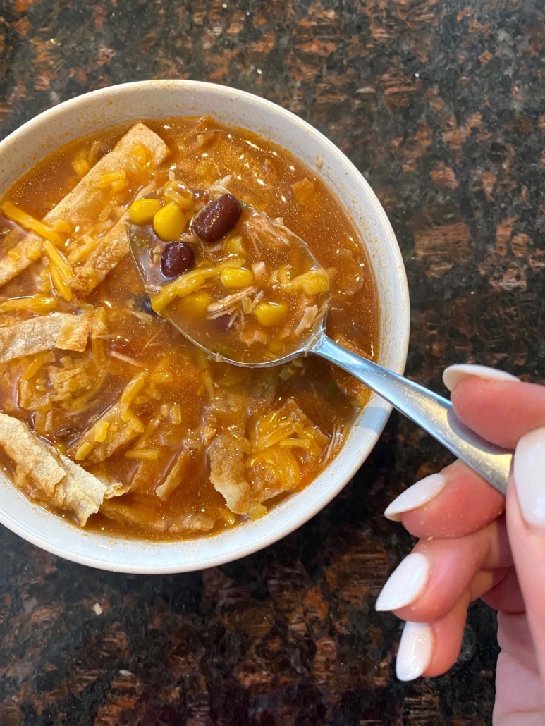 hand holding spoon scooping some soup from bowl