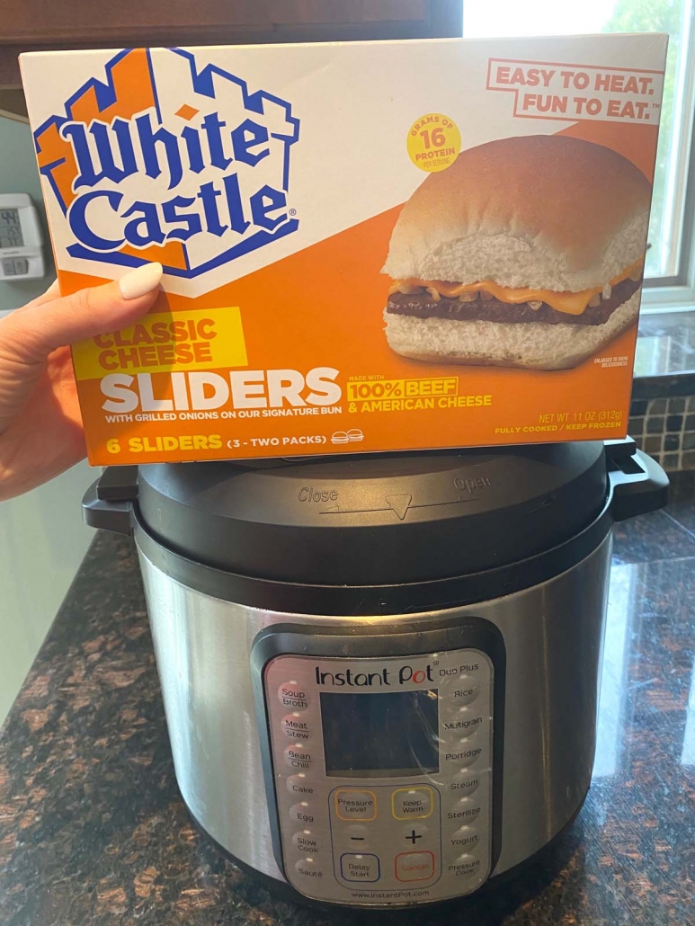 hand holding box of white castle sliders in front of instant pot