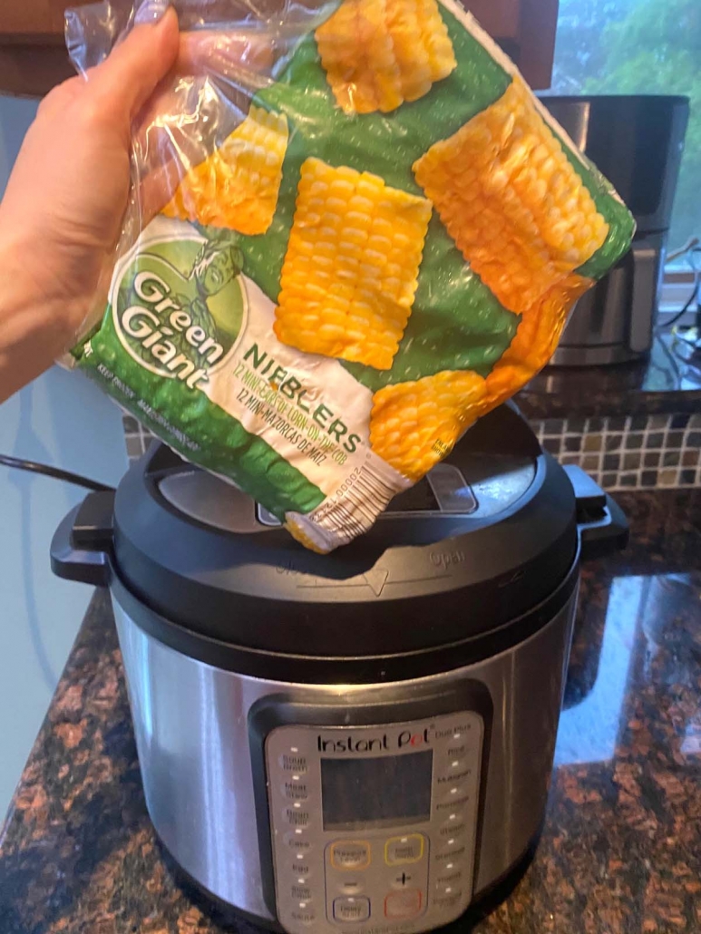 package of corn on the cob held in front of instant pot