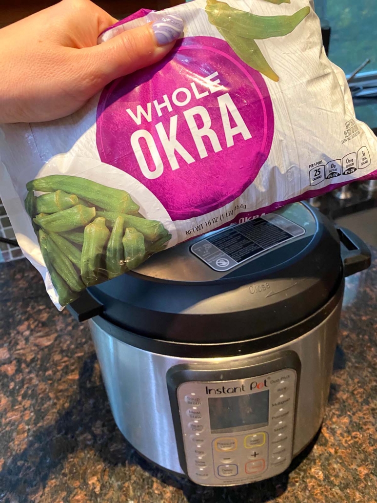 hand holding package of frozen okra in front of instant pot