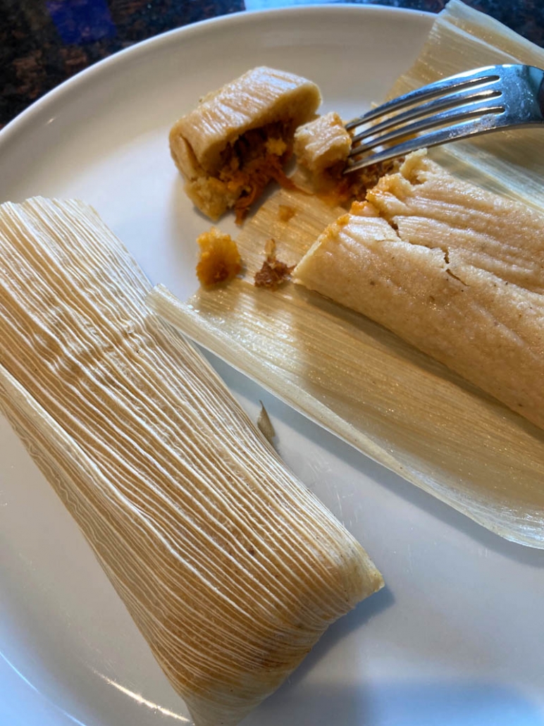 fork stabbing piece of cut open tamale on plate