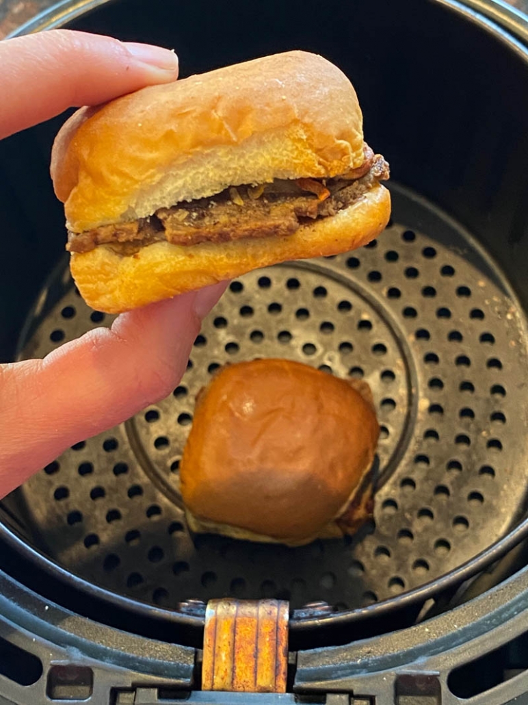 hand holding white castle slider above instant pot and another slider inside