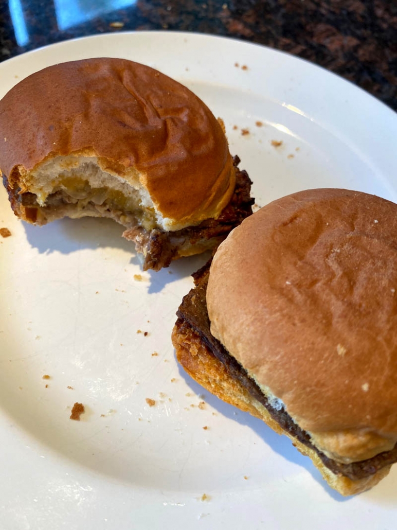 two air fried white castle sliders on a plate with one partially eaten