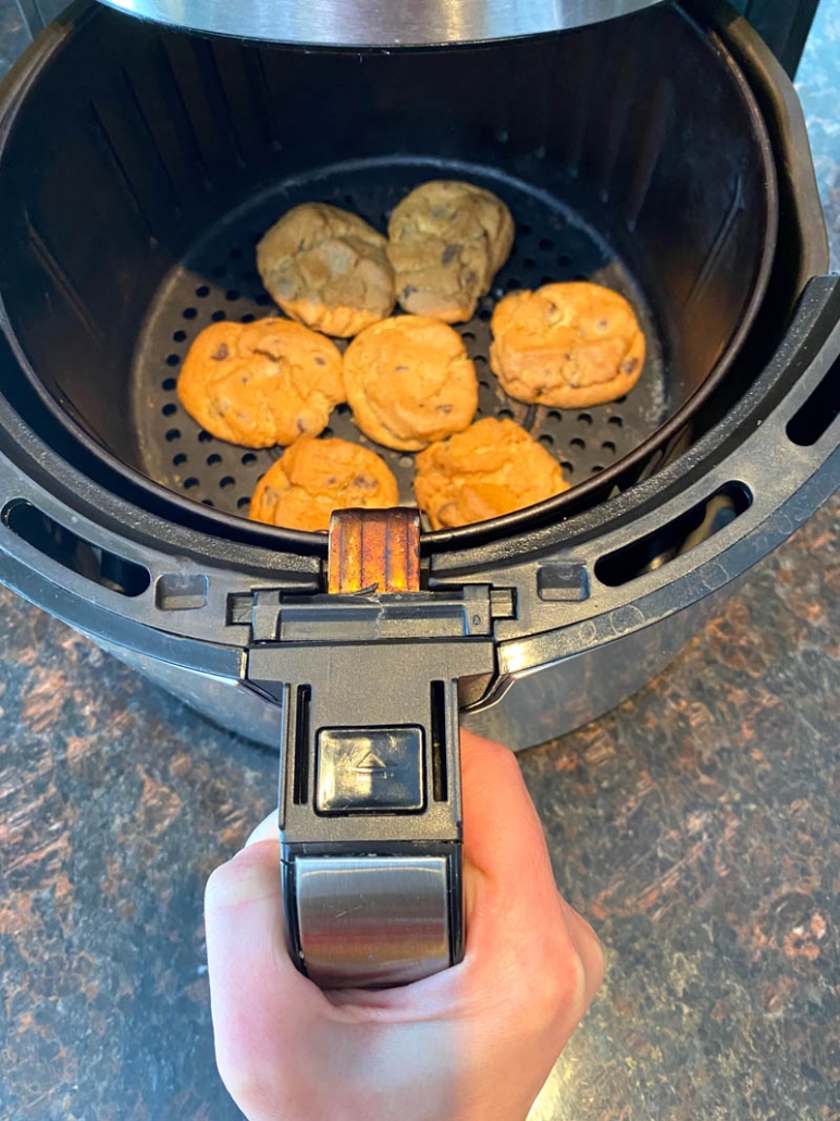 hand holding air fryer basket with cookies inside
