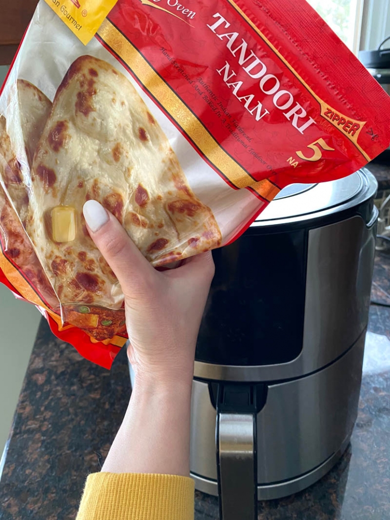 hand holding package of naan bread in front of air fryer