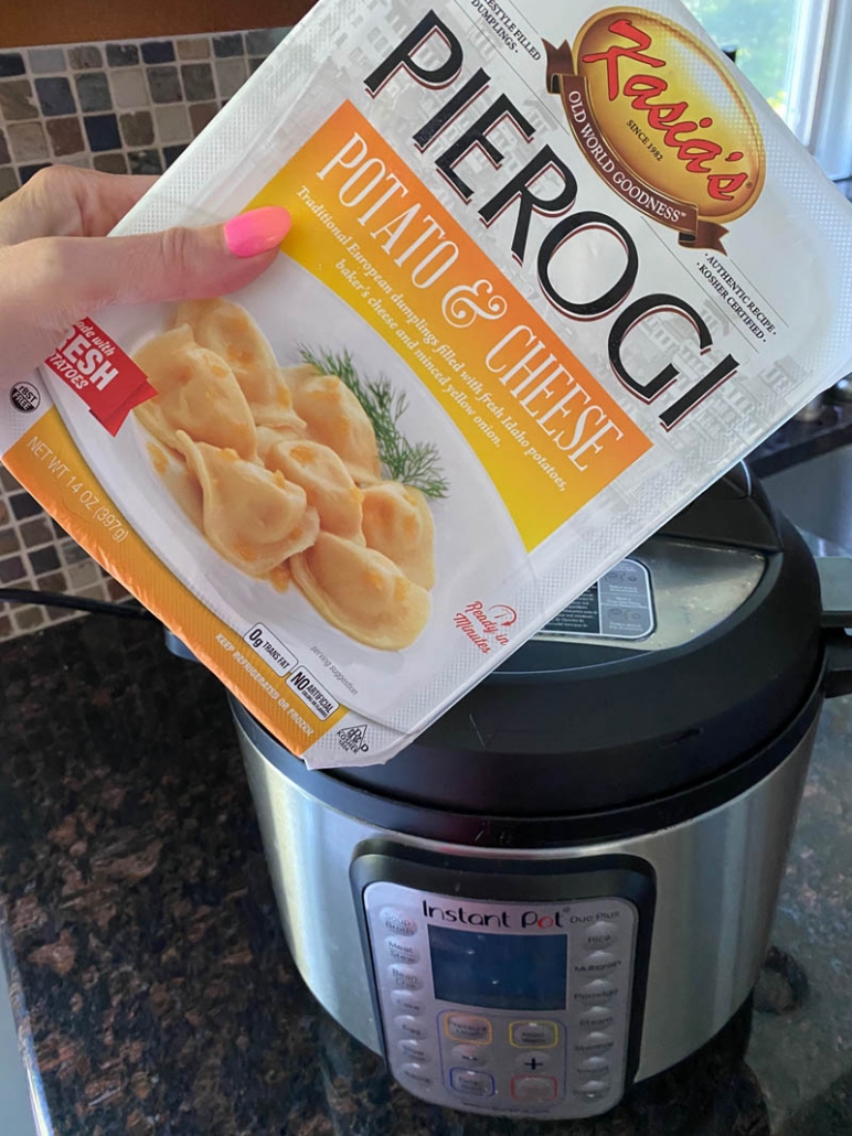 hand holding package of frozen pierogies in front of instant pot