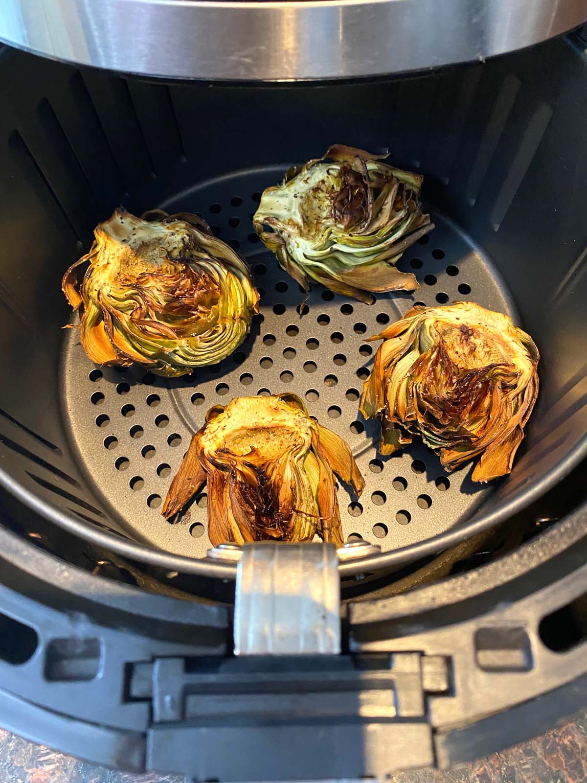 Artichokes in the basket of an air fryer.