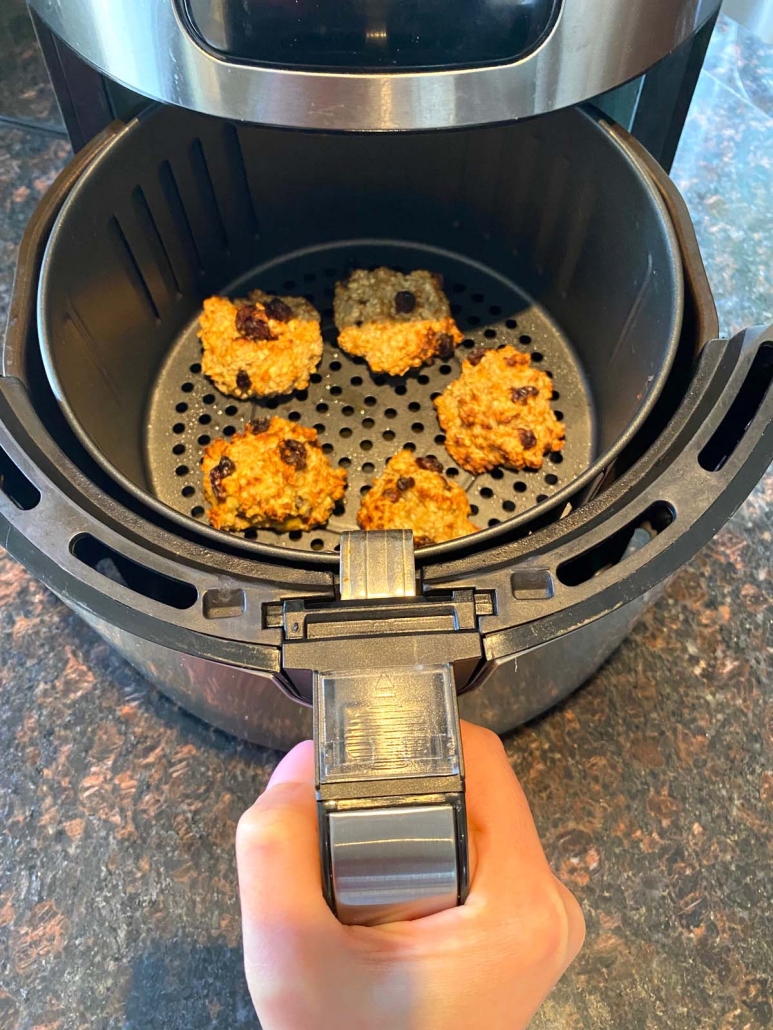hand holding air fryer with banana oatmeal cookies inside