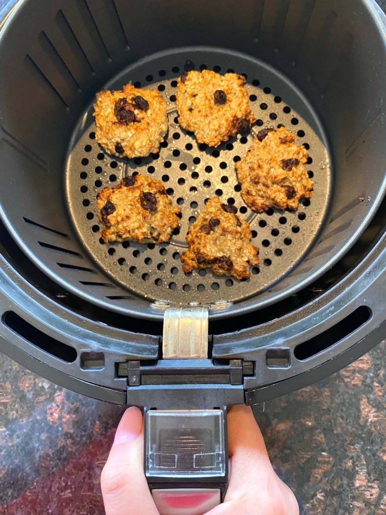 hand holding air fryer with banana oatmeal cookies inside