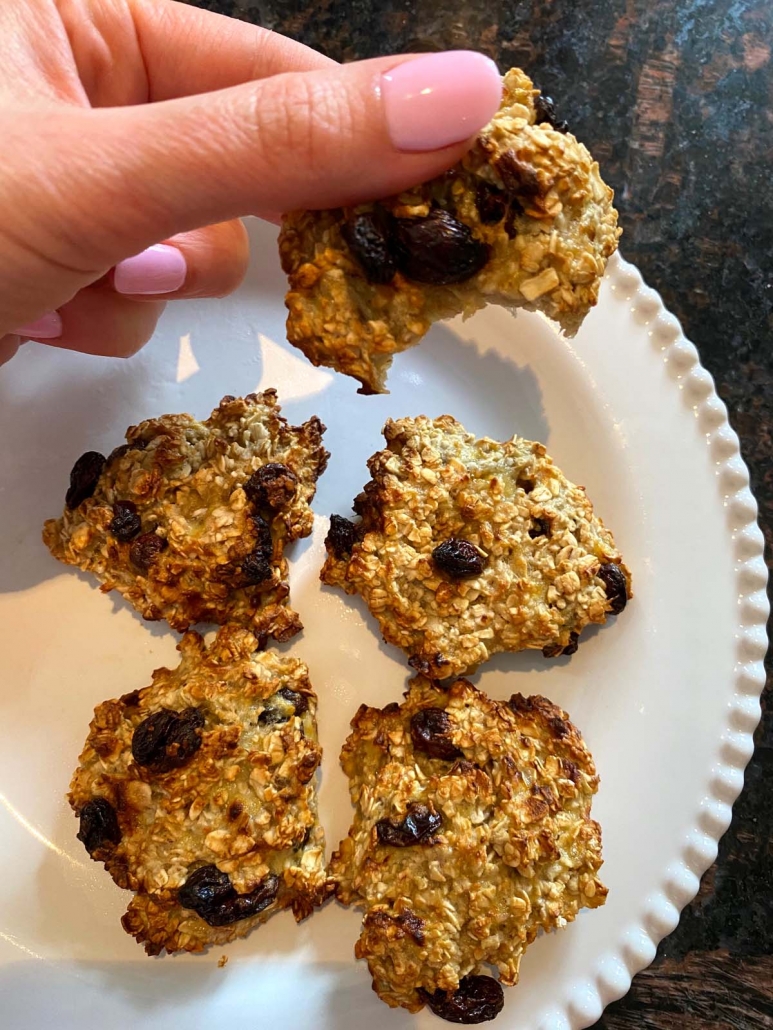 air fried banana oatmeal raisin cookies on a plate and one held overhead with bite taken out
