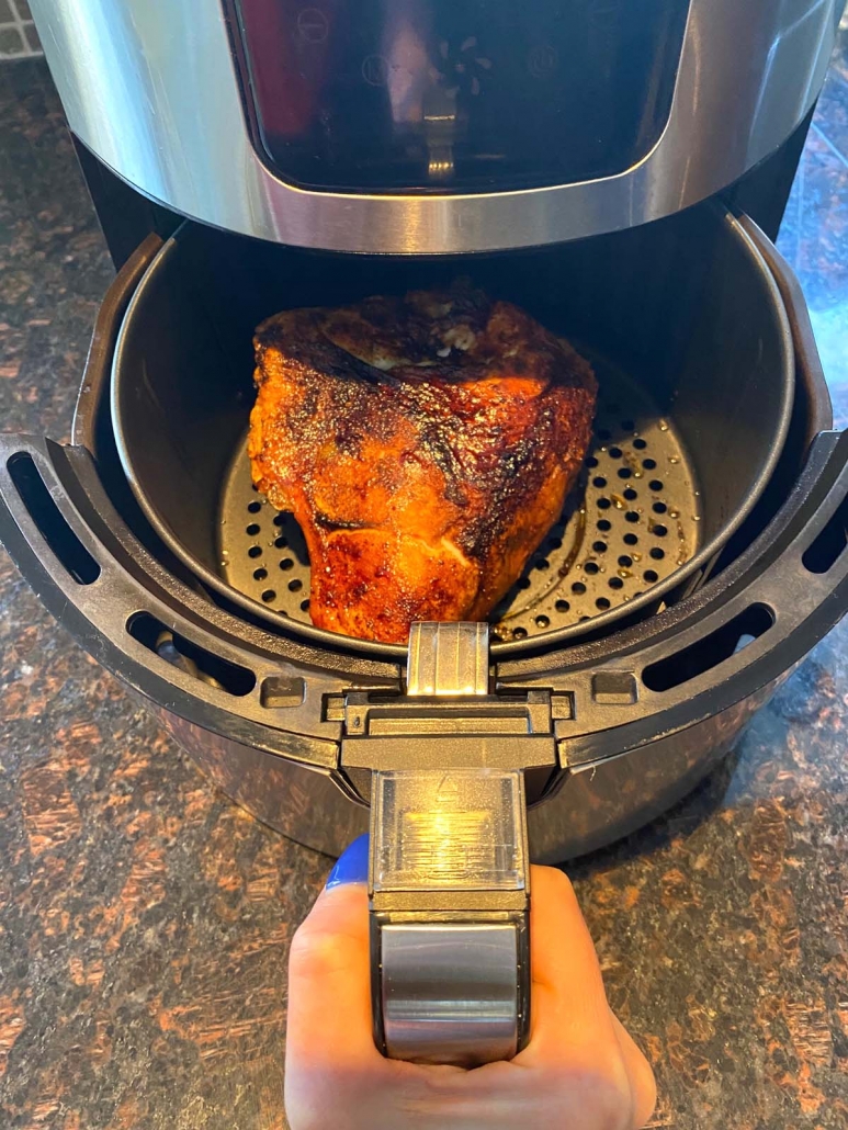 hand holding air fryer basket, pulling out air fried chicken breast