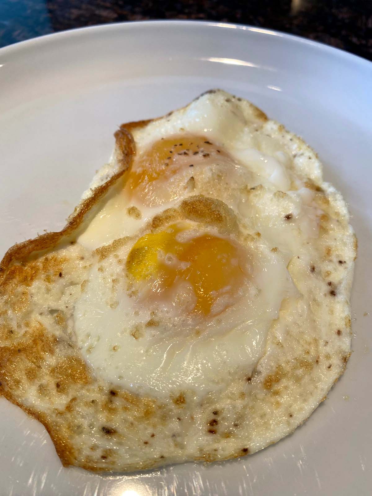 Cooked sunny side up eggs on a plate.