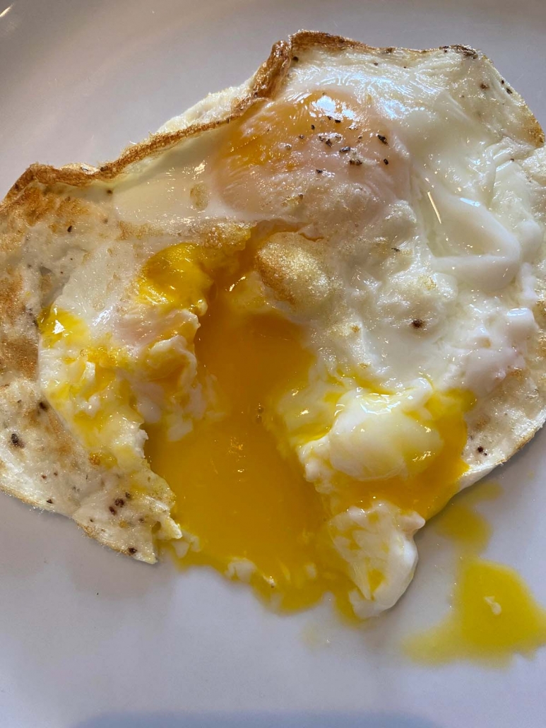 Close up of broken egg with runny yolk.