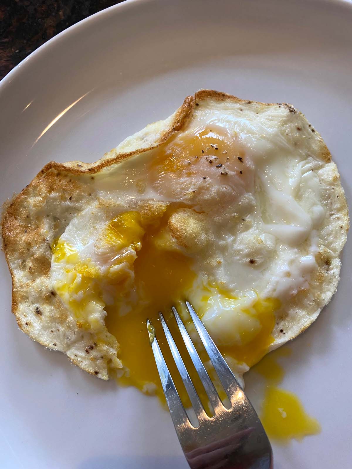 A fork breaking open egg to show runny yolk,