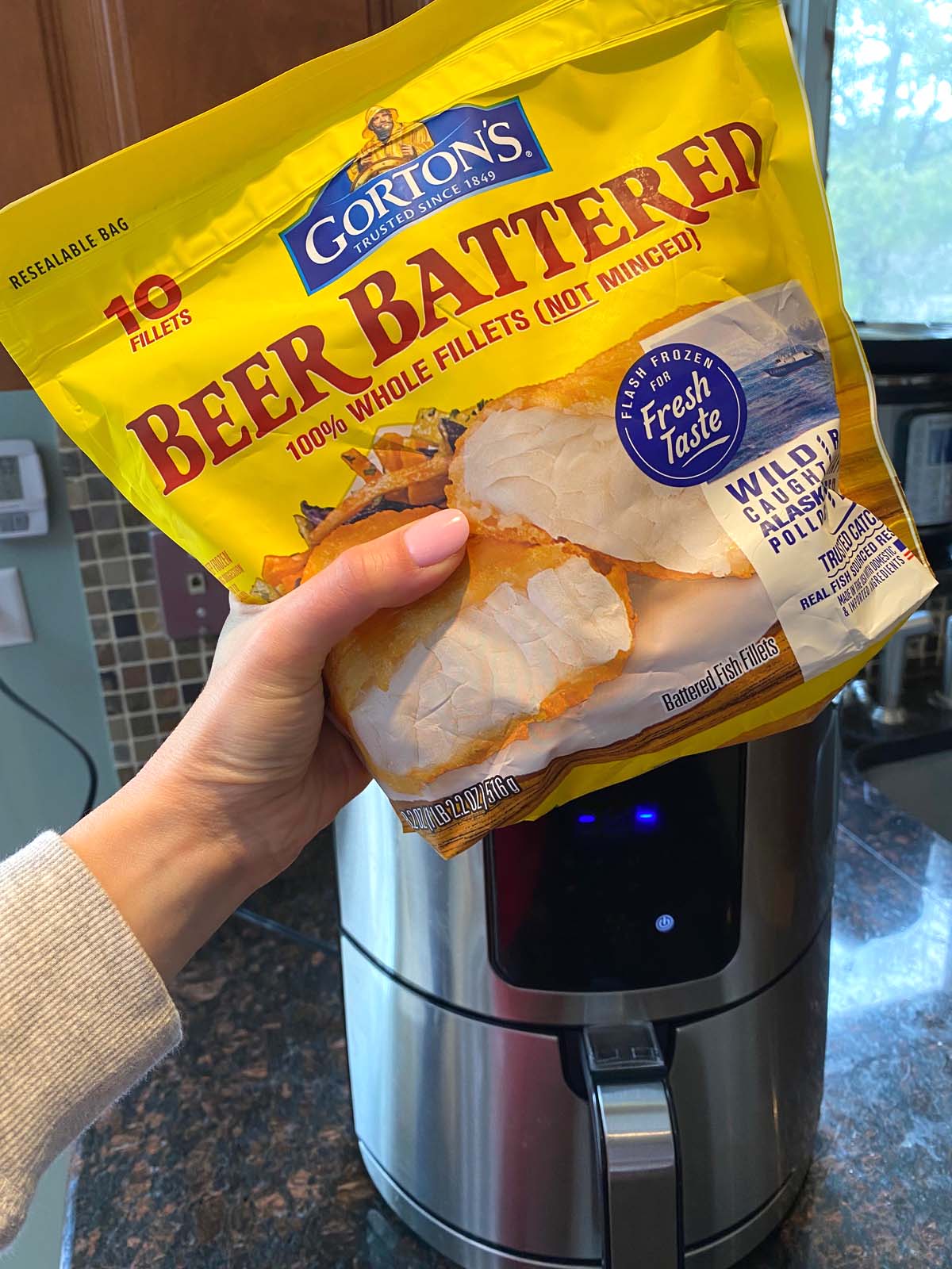 Bag of Gorton's Beer Battered Fish Filets being held in front of an air fryer.