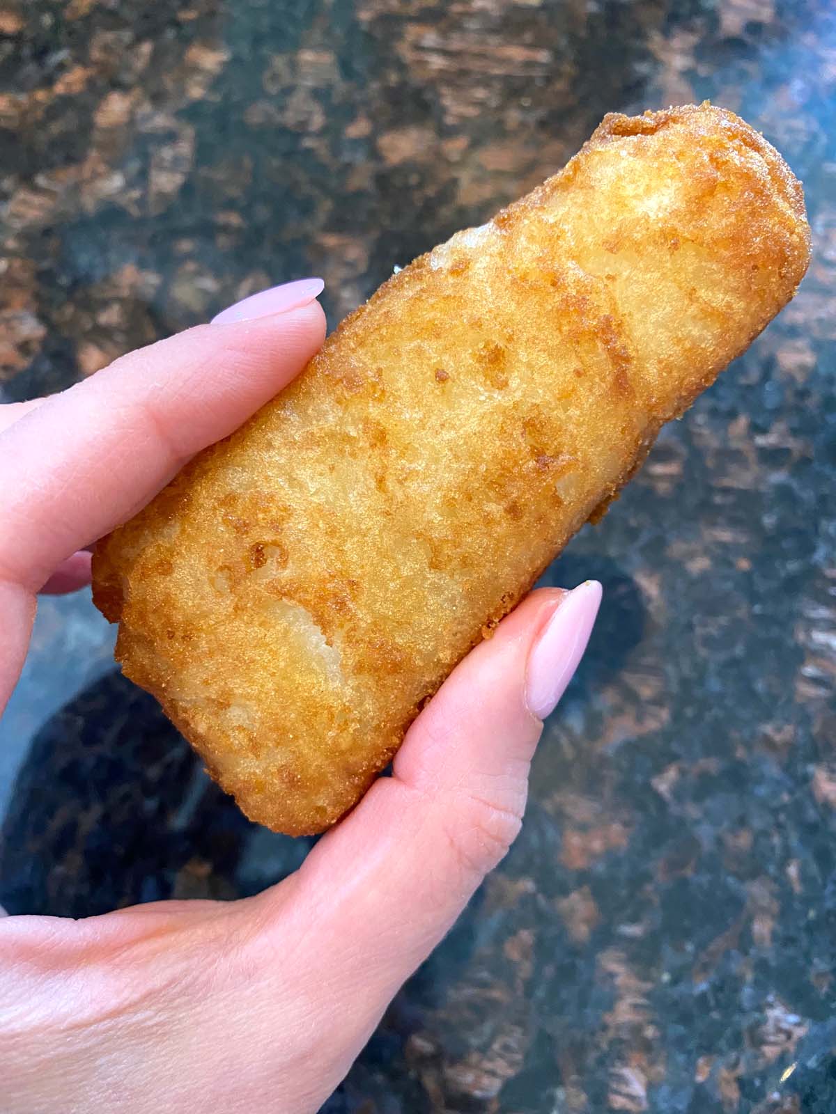 Cooked beer battered fish fillet being held up.