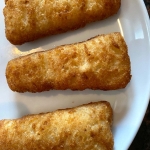 Cooked beer battered fish fillets on a plate.
