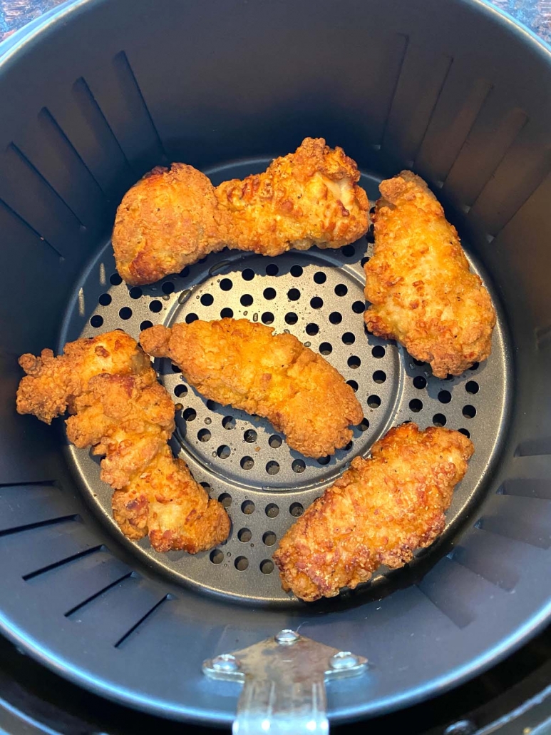air fryer basket with 5 chicken strips inside