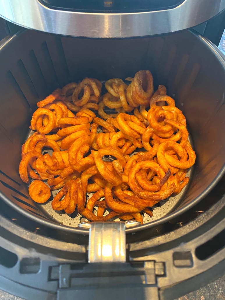 air fryer basket with curly fries inside