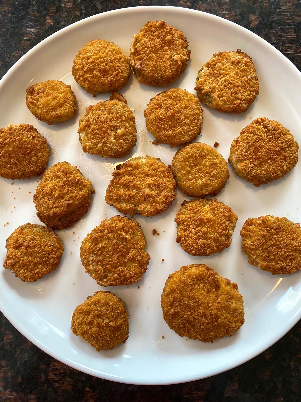 A large plate with cooked fried pickles.