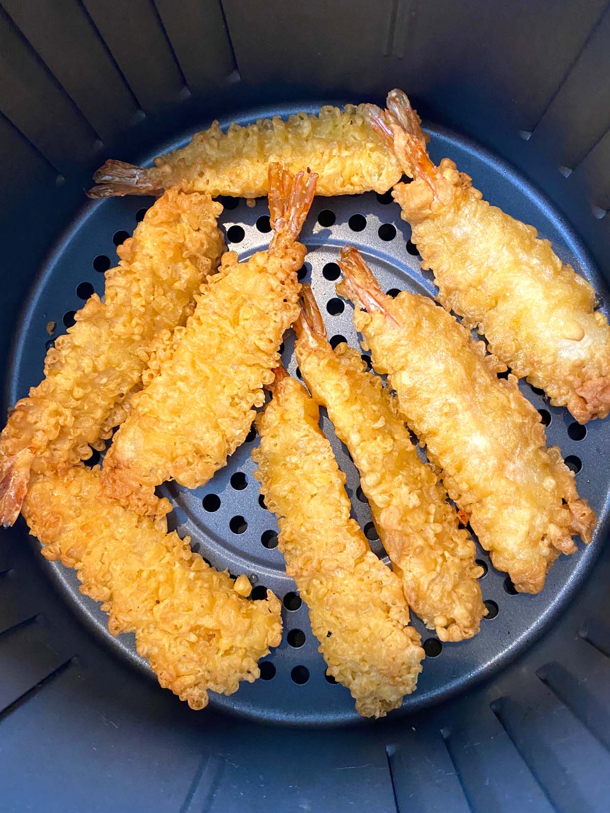 8 pieces of tempura shrimp in an air fryer basket.