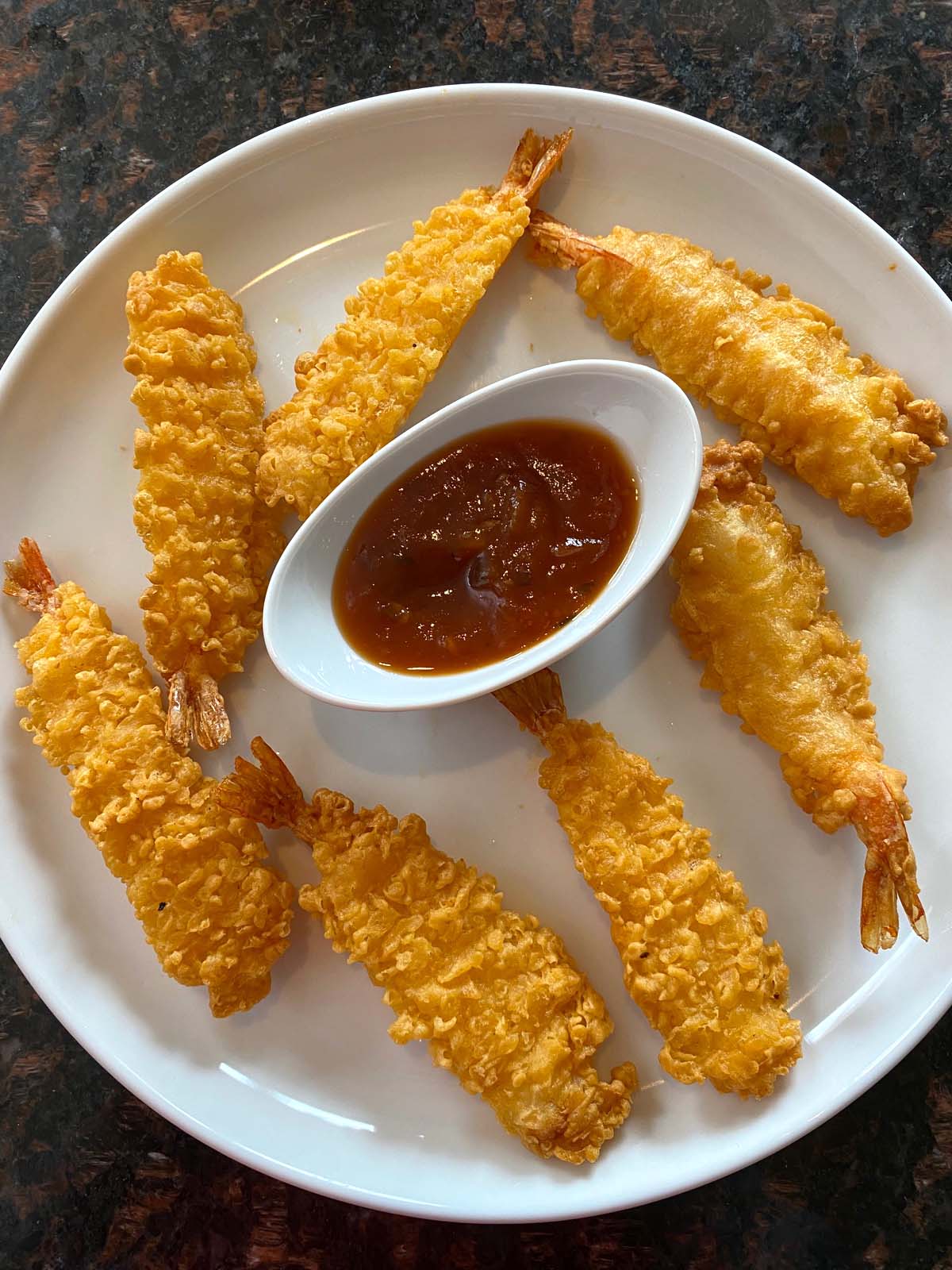 Plate of crispy tempura shrimp served with orange sauce.