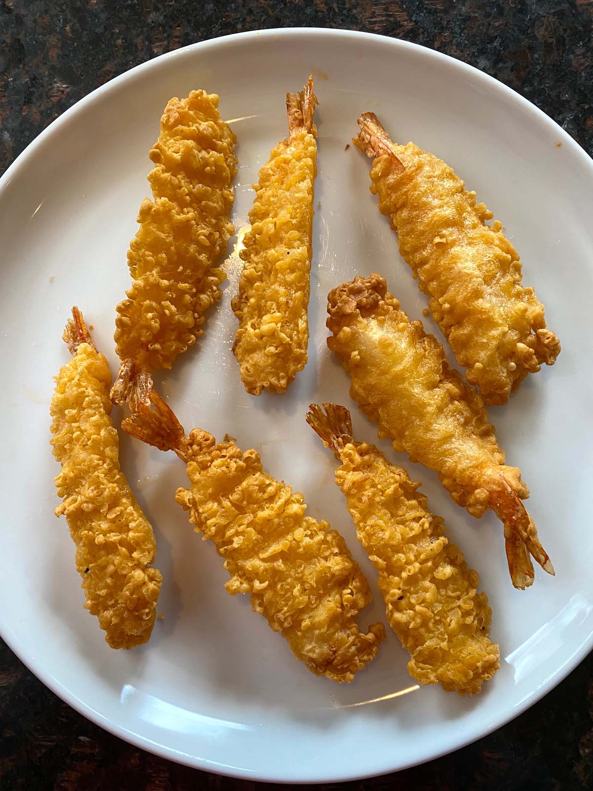 White plate with 8 pieces of cooked crispy shrimp.