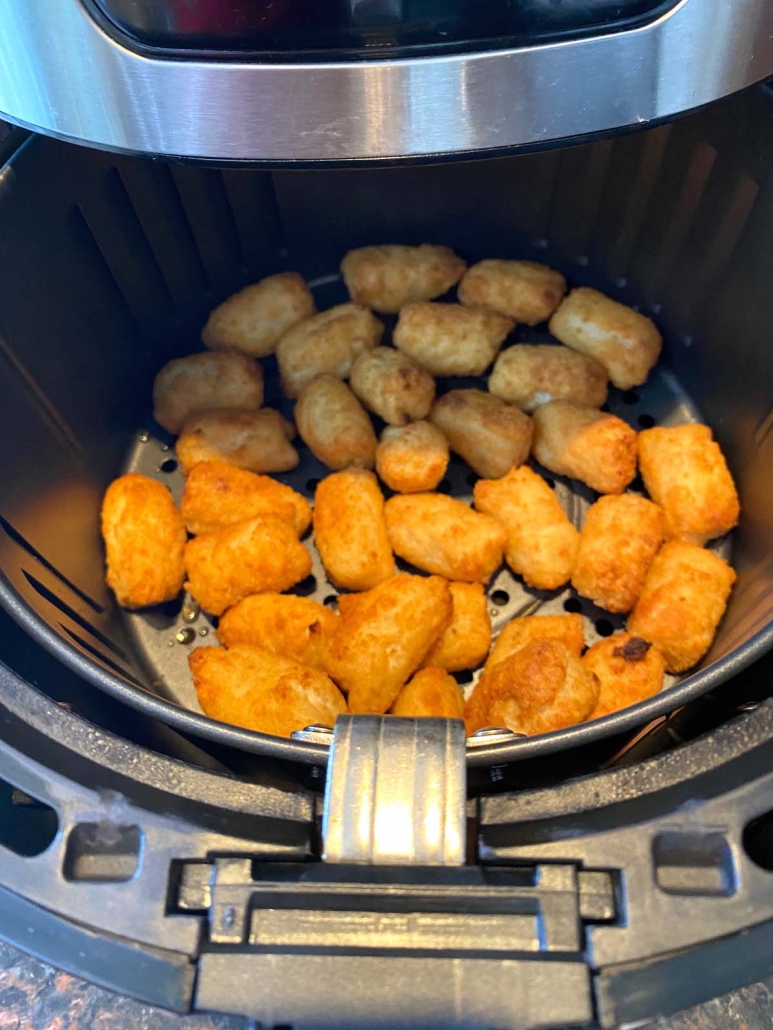 air fryer basket with cooked veggie tots inside