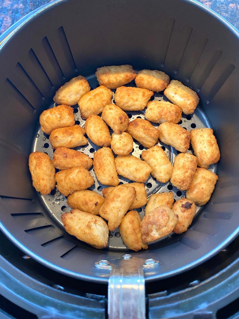 inside of air fryer basket filled with air fried veggie tots