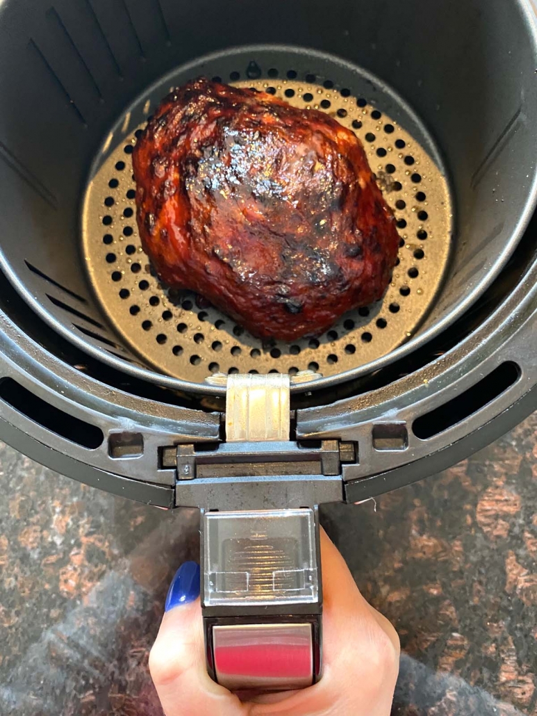 hand holding an air fryer basket with meatloaf inside