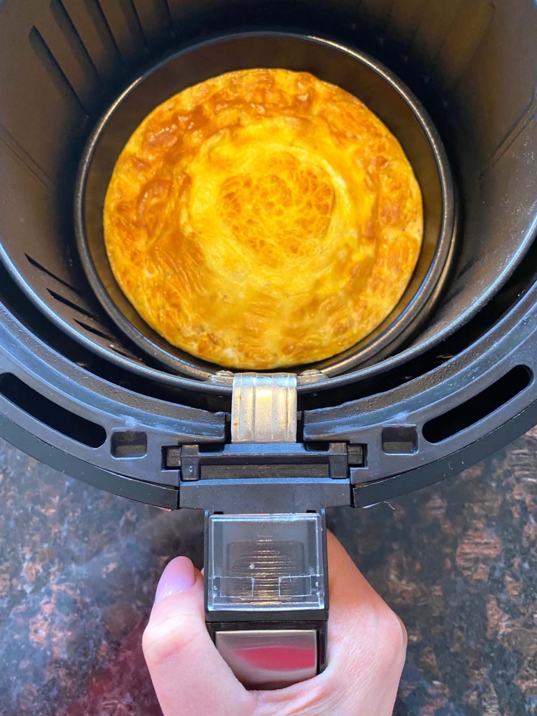hand holding air fryer basket with air fried omelette
