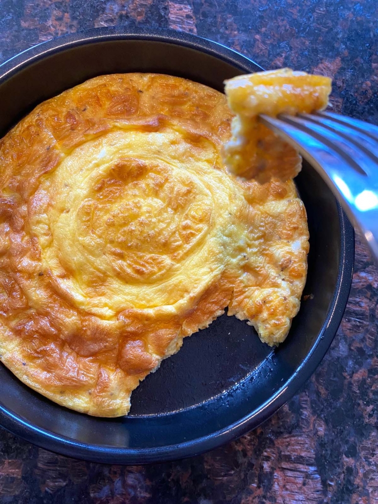 fork holding some omelette above air fried omelette in air fryer pan