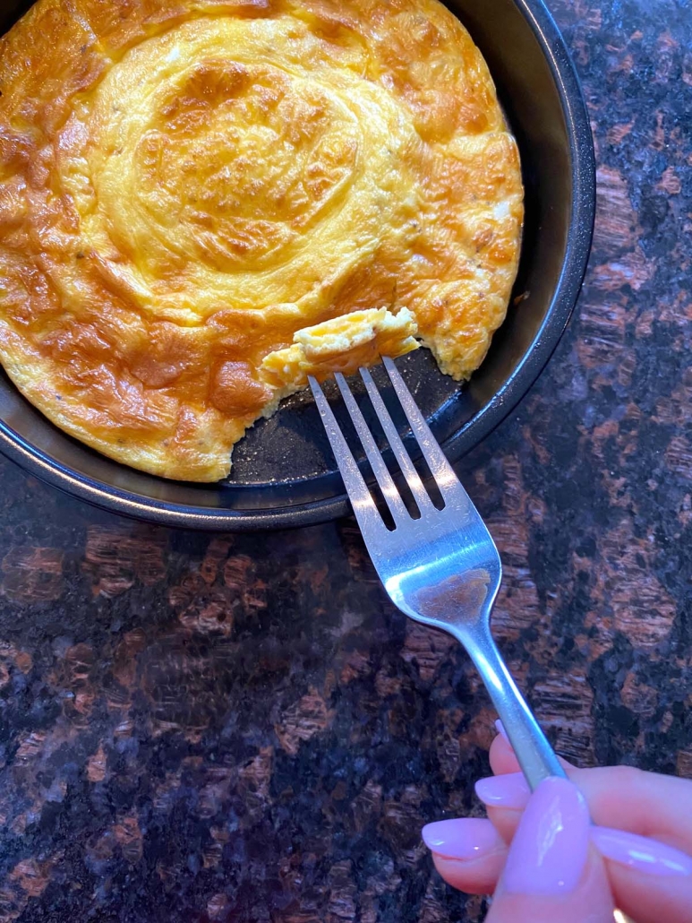 hand holding fork selecting piece of omelette from air fryer pan
