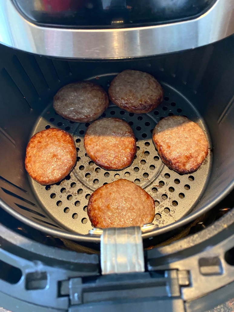 air fryer basket with sausage patties cooking inside