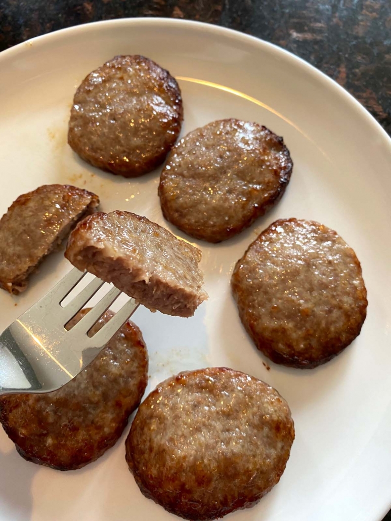 air fried sausage patties on a plate with fork holding half of one