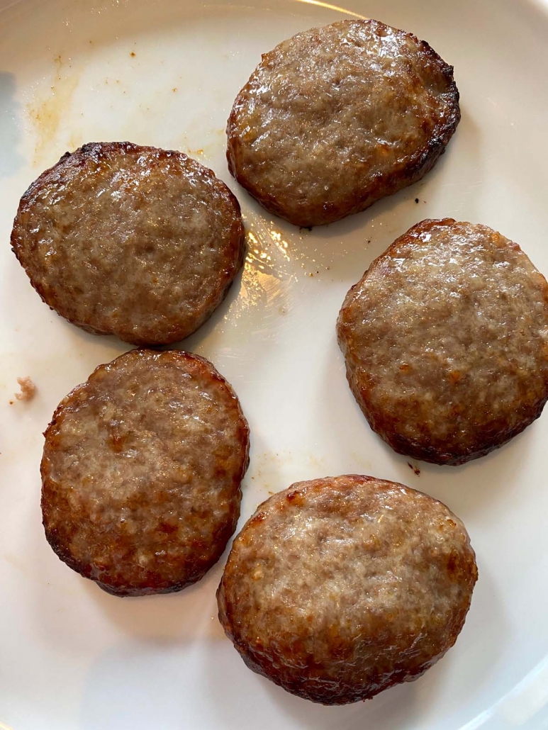 overhead shot of 5 air fried sausage patties on a white plate