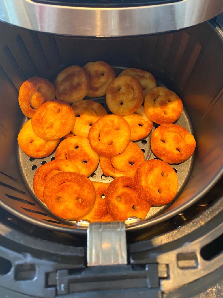 air fryer basket filled with cooked smiley fries