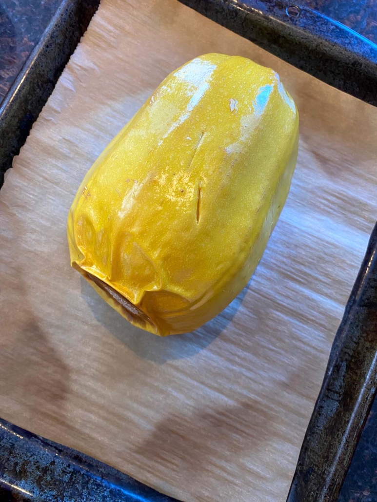 whole spaghetti squash on a parchment lined baking dish