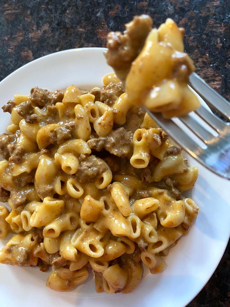 instant pot cooked hamburger helper on a plate with fork holding some in mid-air