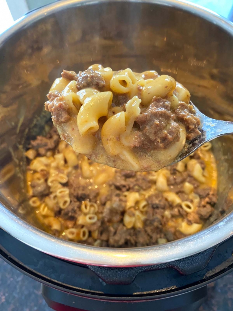 hamburger helper cooked in instant pot with spoon above holding a portion of hamburger helper
