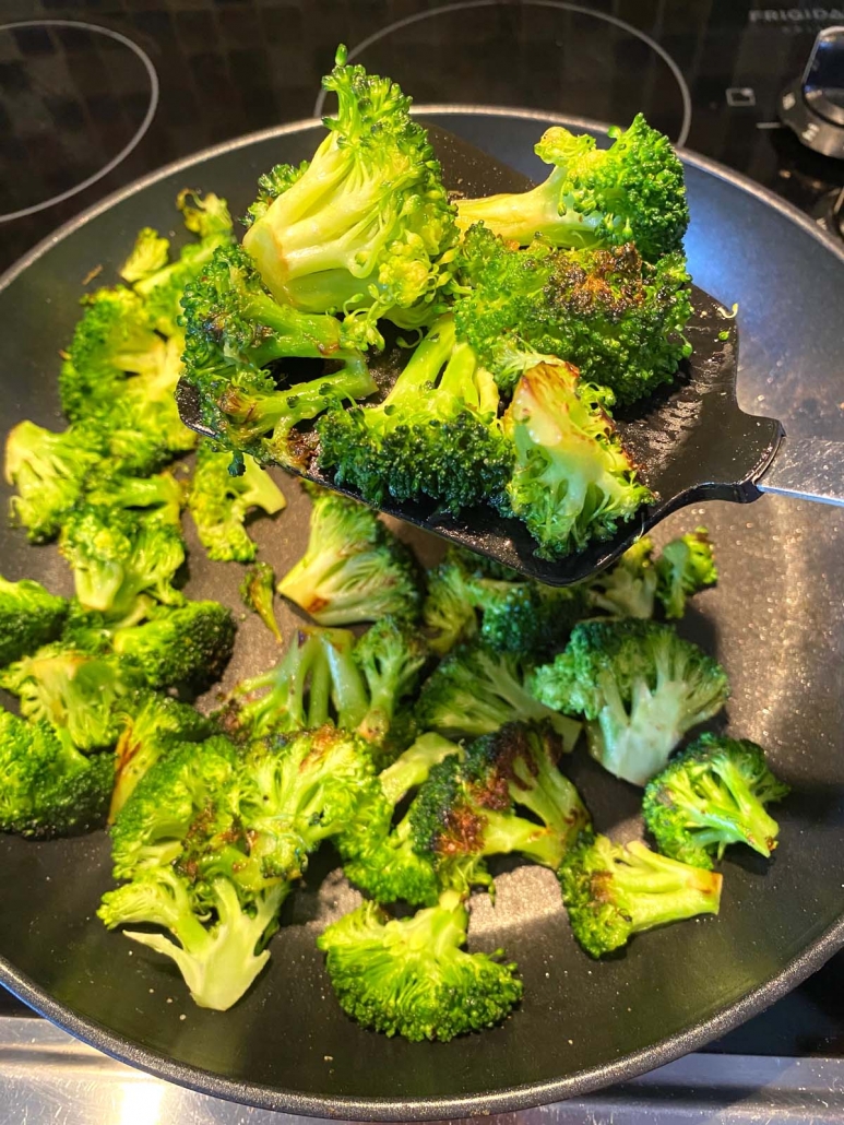 spatula picking up some broccoli from a pan