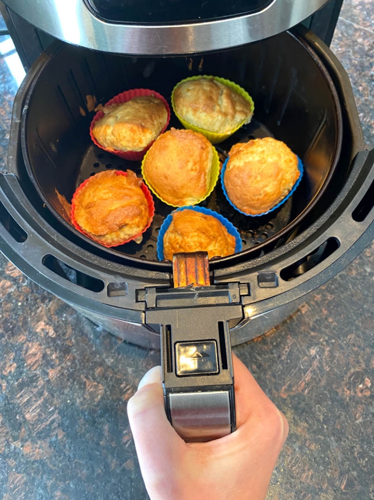 hand holding air fryer with banana muffins inside