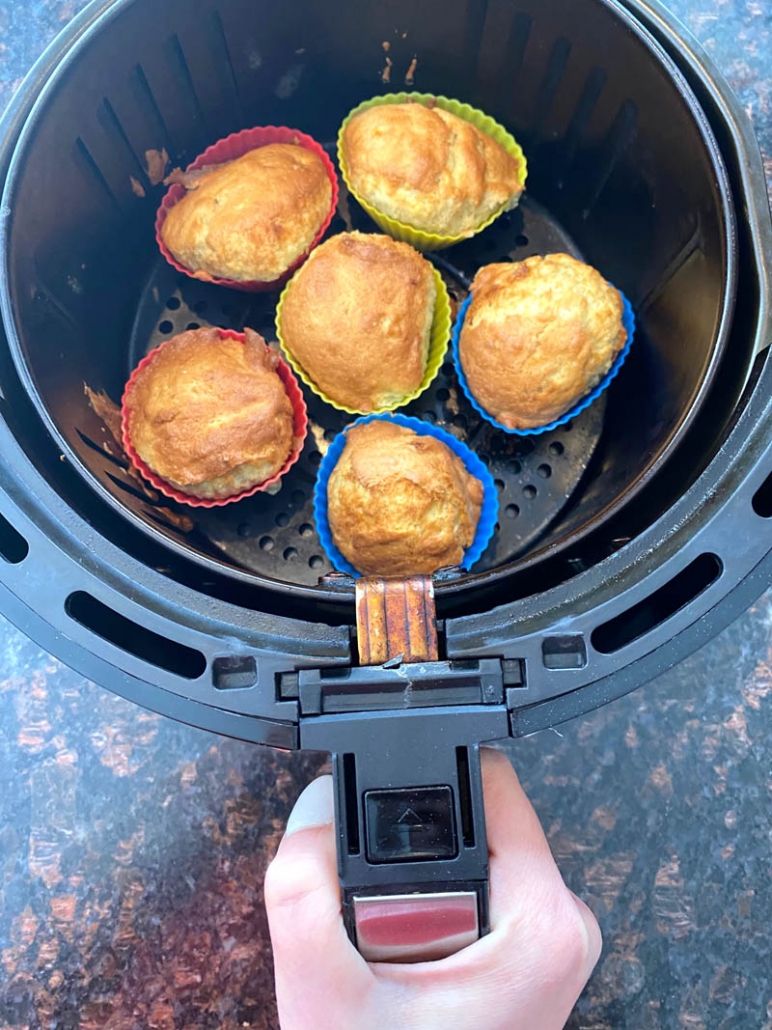 hand holding air fryer basket with muffins inside